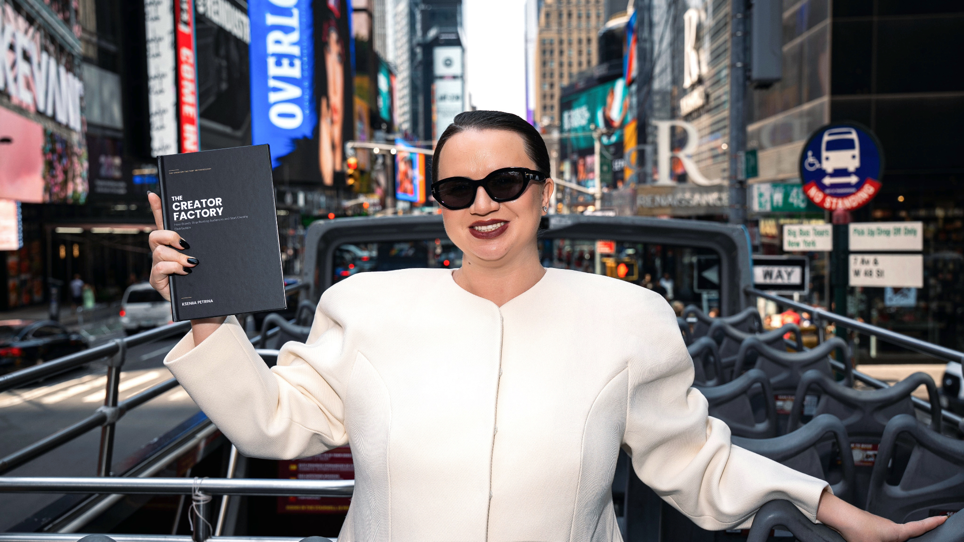 Kseniia Petrina sosteniendo el libro The Creator Factory en Times Square, Nueva York