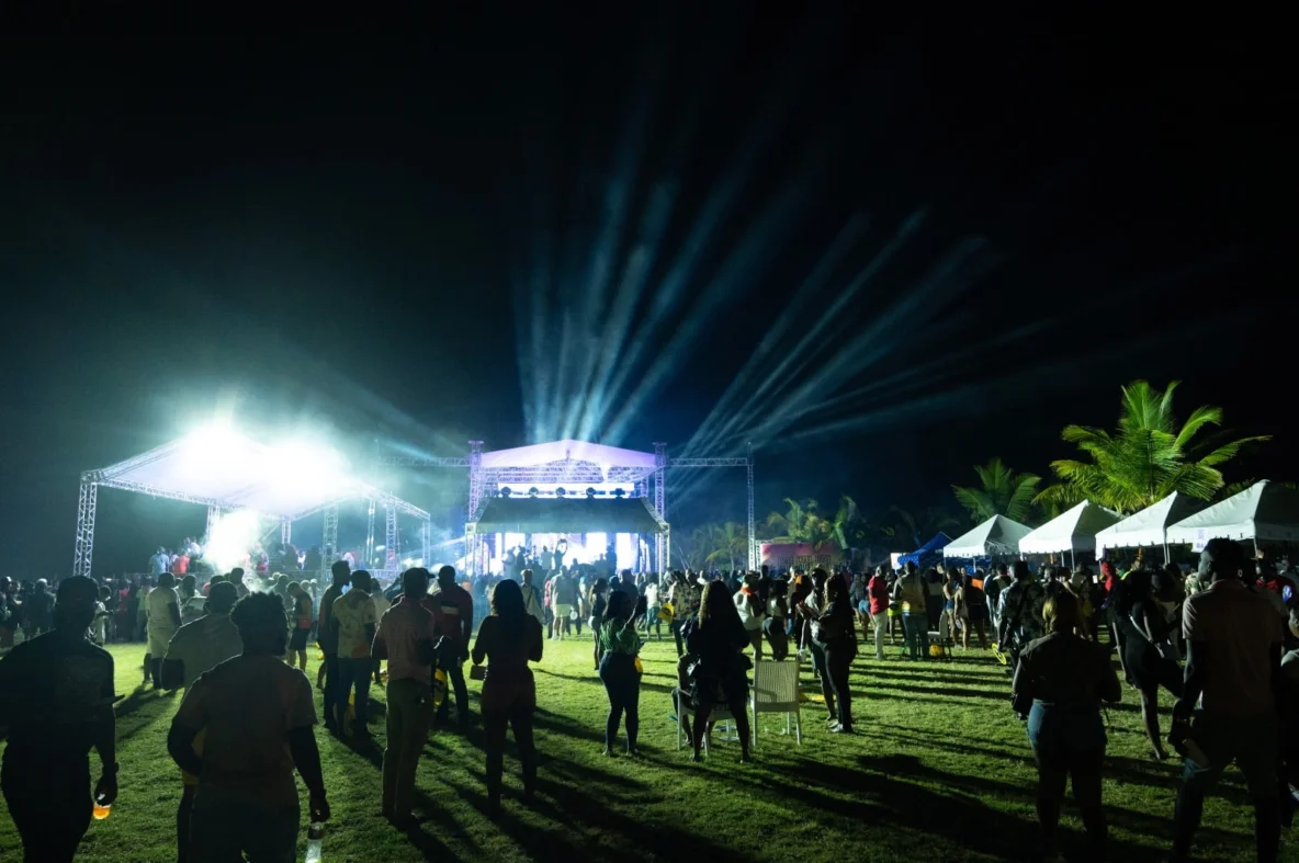 El escenario principal del festival Caribbean Lake Park de noche con reflectores y una multitud de asistentes