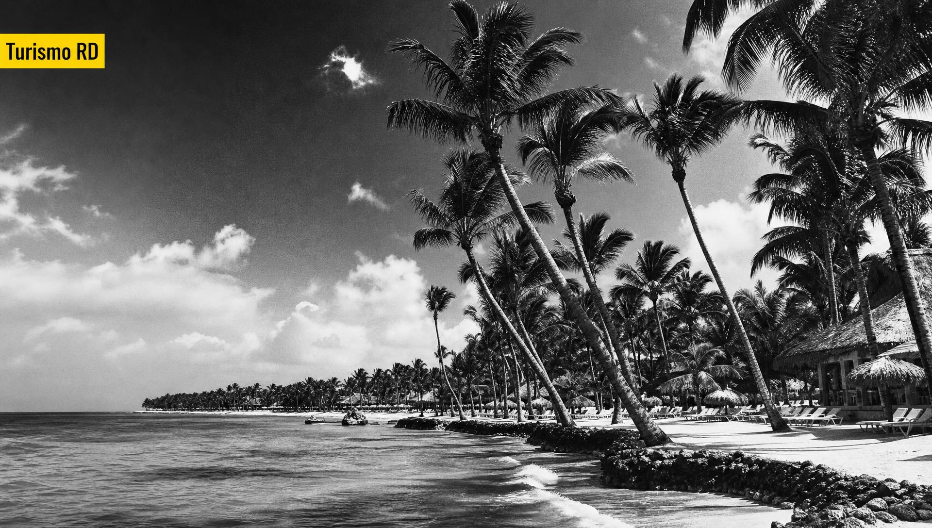Portada editorial blanco y negro de una playa dominicana con palmeras y tag amarillo "Turismo RD" — cuánto cuesta un influencer de turismo en República Dominicana