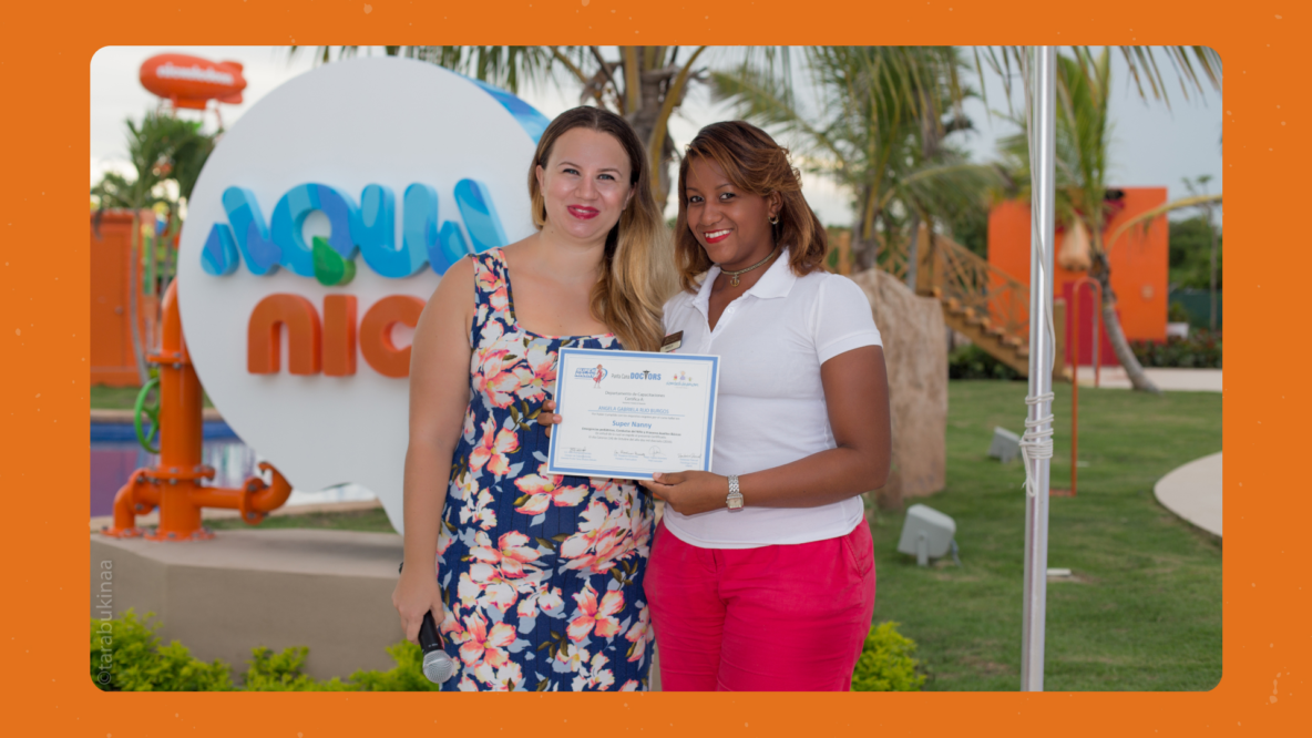 Kseniia Petrina entregando un certificado a una graduada del curso para niñeras en las instalaciones de Aqua Nick, Nickelodeon Hotels Punta Cana